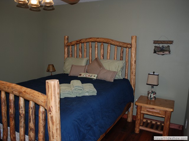 Army green bedroom with queen bed in middle of the cabin.<br/>