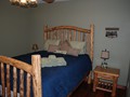 Army green bedroom with queen bed in middle of the cabin.<br/>